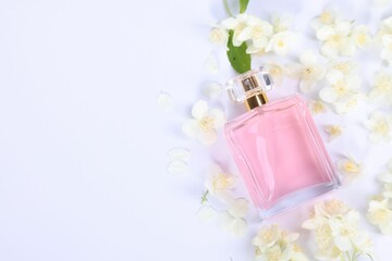 Aromatic perfume in bottle and beautiful jasmine flowers on white background, flat lay. Space for text