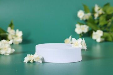 Presentation of product. White podium and beautiful jasmine flowers on green background