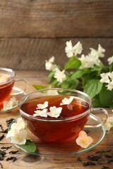 Hot jasmine tea in cups and flowers on wooden table