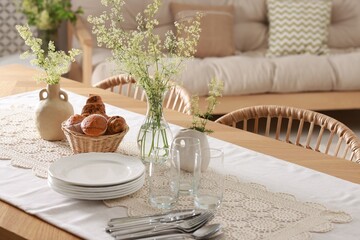 Clean dishes, flowers and fresh pastries on table in stylish dining room