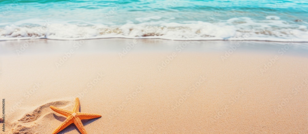 Fototapete Starfish lying on the sandy shore of a beach as a wave is rolling in towards it. with copy space image. Place for adding text or design
