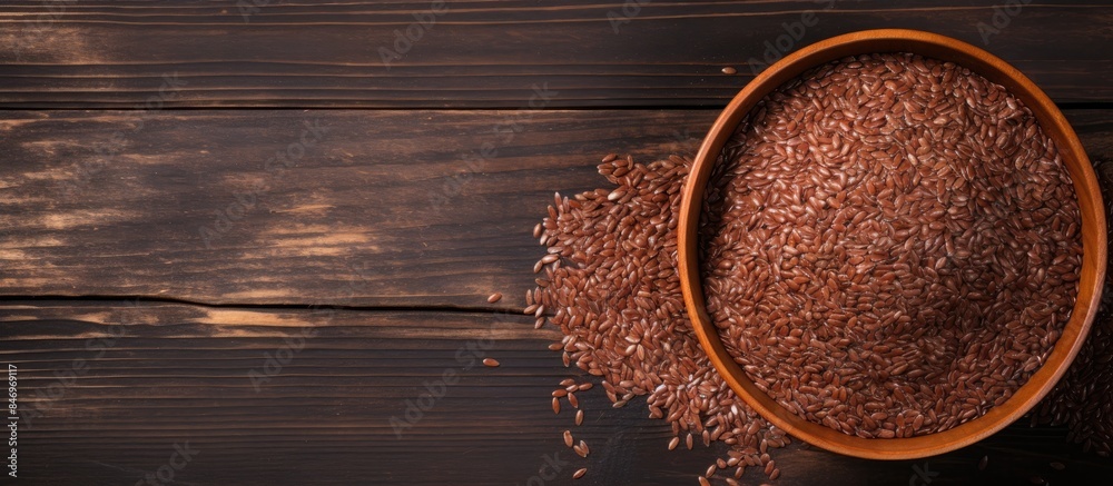 Poster Wooden bowl filled with brown rice placed on a wooden table surface. with copy space image. Place for adding text or design