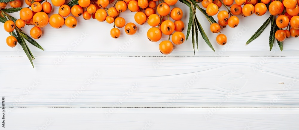 Poster Orange berries and green leaves arranged on a white wooden table, creating a vibrant and fresh display. with copy space image. Place for adding text or design