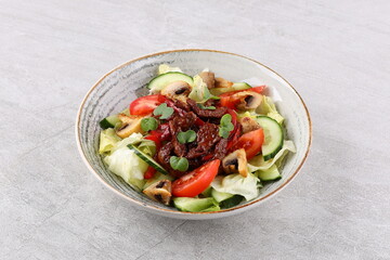 Asian beef salad with vegetables and nuts in a white bowl on a dark background. Asian food concept.