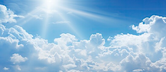 Sun piercing through beautiful white clouds in a clear blue sky, creating a radiant scene. with copy space image. Place for adding text or design
