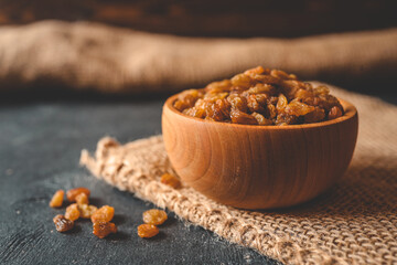 Golden dried raisins in wooden bowl on a wooden table