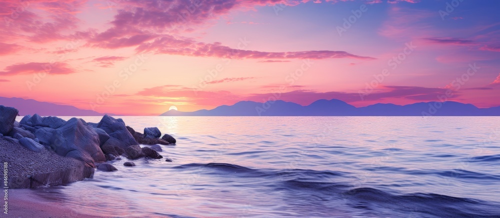 Poster vibrant purple hues illuminate the sky as the sun sets over the ocean, casting a serene glow on the 