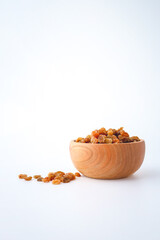 Golden dried raisins in wooden bowl isolated on white background