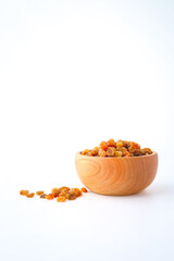 Golden dried raisins in wooden bowl isolated on white background