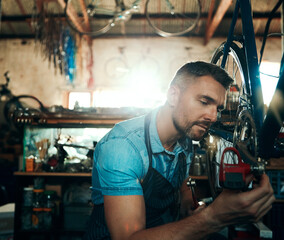 Bicycle technician, repair and working in shop with tyre, chain and tools for maintenance or cycling. Man, mechanic and bike in workshop as handyman for gear, inspection and safety with service
