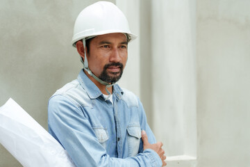 Multiethnic construction engineers wearing hard hats stand with folded arms holding structural...