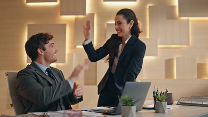 Happy team rejoicing success looking computer at office. Colleagues giving five
