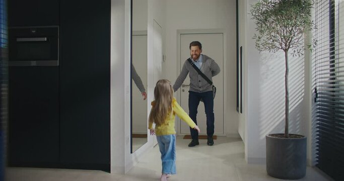 Loving Caucasian man entering his apartment. With one hand hiding teddy bear behind his back. After hugging daughter making surprise by gifting toy to beloved kid. Surprised child.