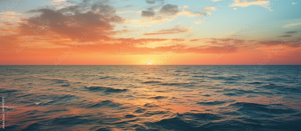 Fototapete The sun setting over the sea, casting a golden glow on the water with fluffy clouds in the sky. with copy space image. Place for adding text or design