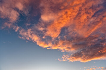Morgen- oder Abendhimmel mit aufgelockerter, vom Wind verwirbelter, orangefarbener Bewölkung, bei klarer Luft und blauem Himmel