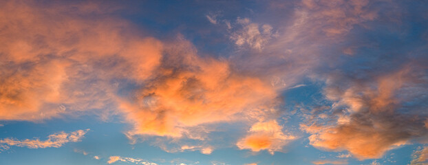 Morgen- oder Abendhimmel mit aufgelockerter, vom Wind verwirbelter, orangefarbener Bewölkung, bei klarer Luft und blauem Himmel