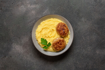 Mashed potatoes with cutlet in a bowl on a dark rustic background. Top view, flat lay