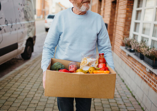 Delivery guy with cardboard box full of groceries