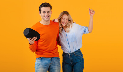 Obraz premium attractive stylish young couple holding wireless speaker