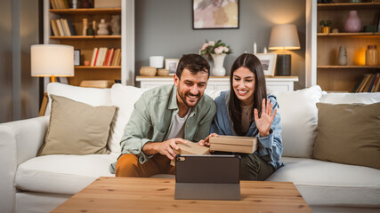 Couple open birthday gift together via video call on tablet at home