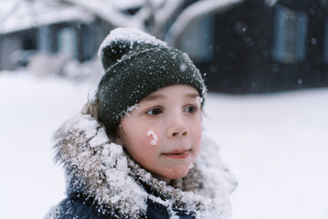 happy boy in winter clothing spending day in snow