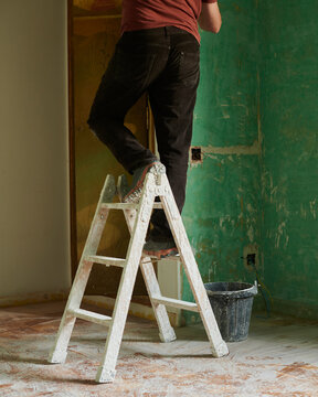Man working at home renovation work with painting ladder