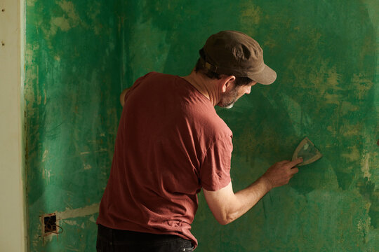 Handyman doing renovation work with spatula inside a room at home