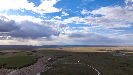 Fototapeta premium Vast prairie desert landscape in Badlands South Dakota with sunshine, farmland, clouds and blue sky dramatic view in nature's hot climate