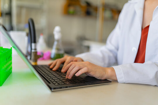 Crop woman scientist browsing laptop while working in laboratory