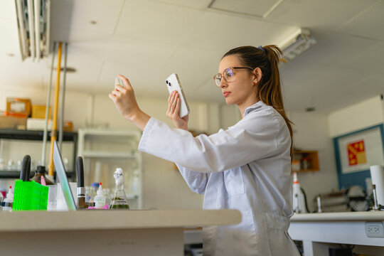 Woman scientist taking picture mobile phone in laboratory