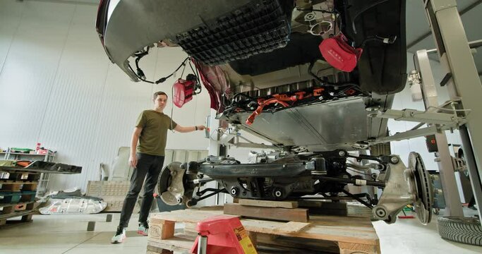 Mechanic inspecting a disassembled electric car engine in a workshop. Automotive maintenance, repair, and EV service concept. EV repair concept. Auto Service, Electric Car Battery Handling.