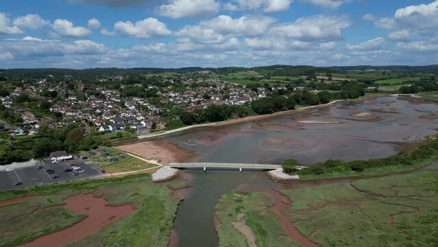 Budleigh Salterton, Devon, England: DRONE VIEWS: A bridge over the River Otter estuary with the town in the background. The Jurassic Coast is a popular UK holiday destination (Clip 2).
