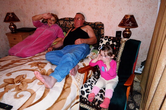 grandfather with grandmother and granddaughter are watching TV