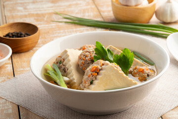 Clear Soup with flat Tofu stuffed with seasoning minced pork in white bowl. ( Kang Jued Tao Hoo Moo Sub)