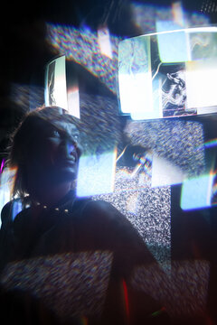 Woman standing in front of black and white ad screens in the dark