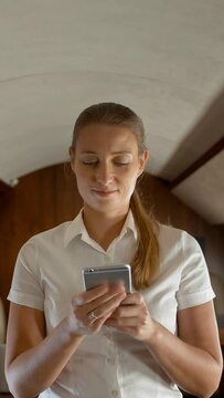 Portrait of busy young woman typing messages in smartphone in private jet. Deal working female with cell phone in airplane chatting on selphone staying in the cabin. 4k UHD Vertical shot.