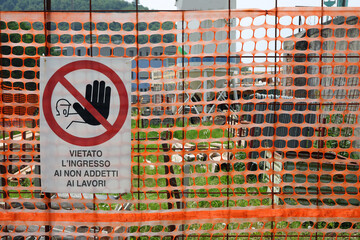 sign with italian text warning unauthorized personnel to stay out behind orange protective netting in the Construction site