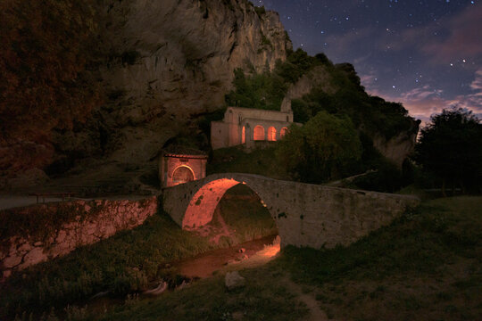 hermitage of Santa Maria de la Hoz, in Tobera, Burgos on a night with the starry sky and the bridge and the hermitage illuminated by warm light