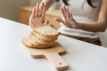 Gluten allergy, asian young woman hand holding, refusing to eat, looking at bread slice on plate in...