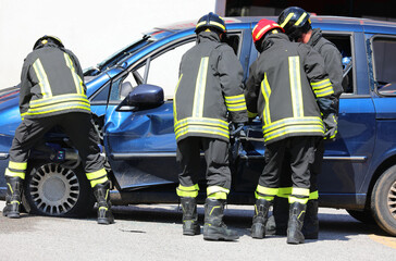 firefighters using hydraulic shears and jaws of life to open the door of a crashed car after an accident in order to free the injured person