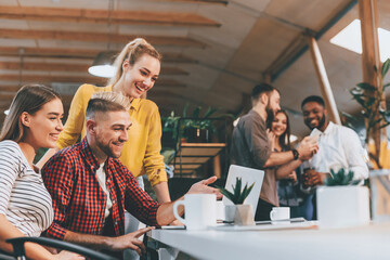 Young colleagues working on laptop and discussing new project in office