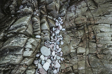 runde, helle Steine auf eckigen, dunklen Felsen