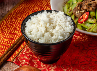 Boiled White Rice with chopsticks and spoon served in bowl isolated on napkin side view on wooden table of taiwanese food