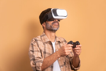 joyful senior man playing videogame with VR headset in all beige colors. virtual reality, gaming, leisure concept.