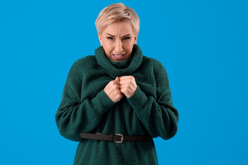 Scared mature woman on light blue background