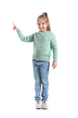 Cute little girl in knitted sweater pointing at something on white background