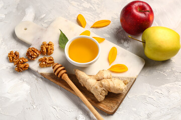 Board with bowl of sweet honey, walnut, ginger and apples on grunge background