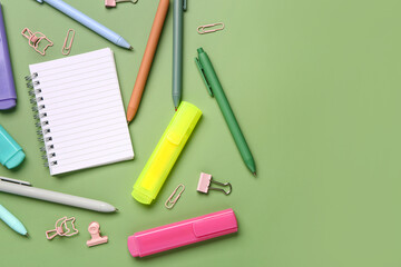 Blank notebook with school stationery on green background