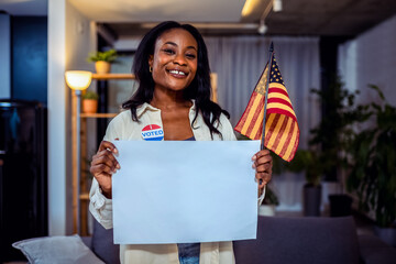 A Black woman is holding a white paper, an American flag, and a badge that says 