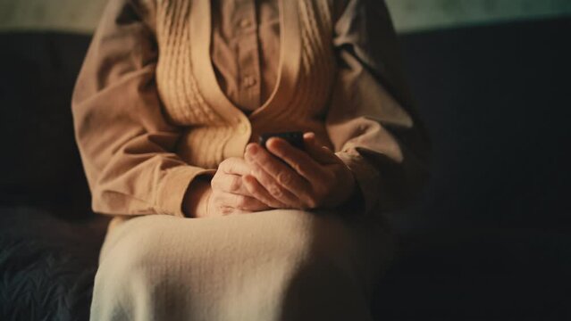Lonely elderly woman holding mobile phone, waiting for call from son, sadness
